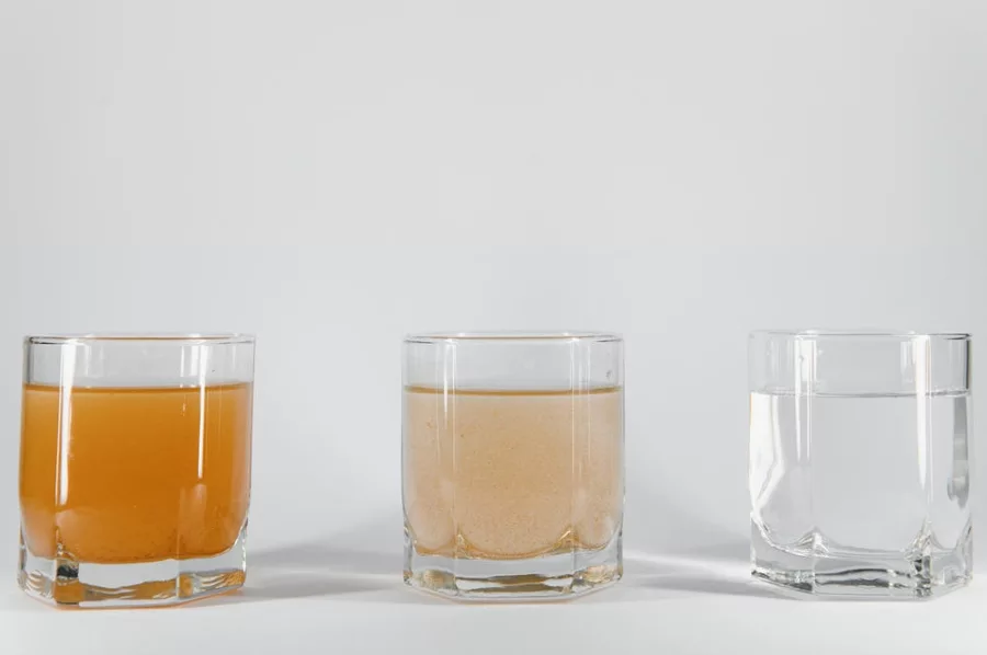 Three glasses showing iron-stained water becoming clear