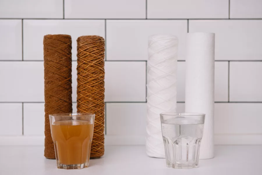 Sand filter cartridges beside glasses of unfiltered and filtered water